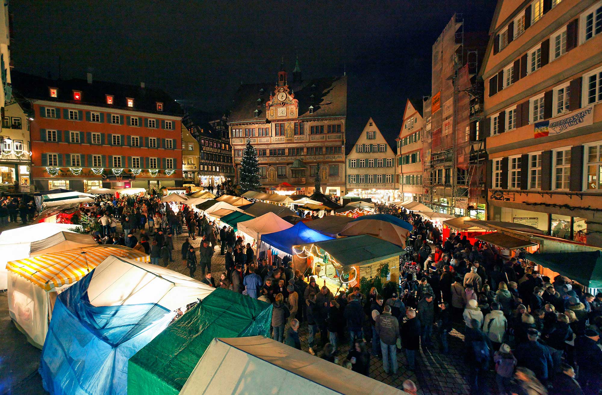 Weihnachtsmarkt vor dem Tübinger Rathaus am Abend mit vielen Ständen 